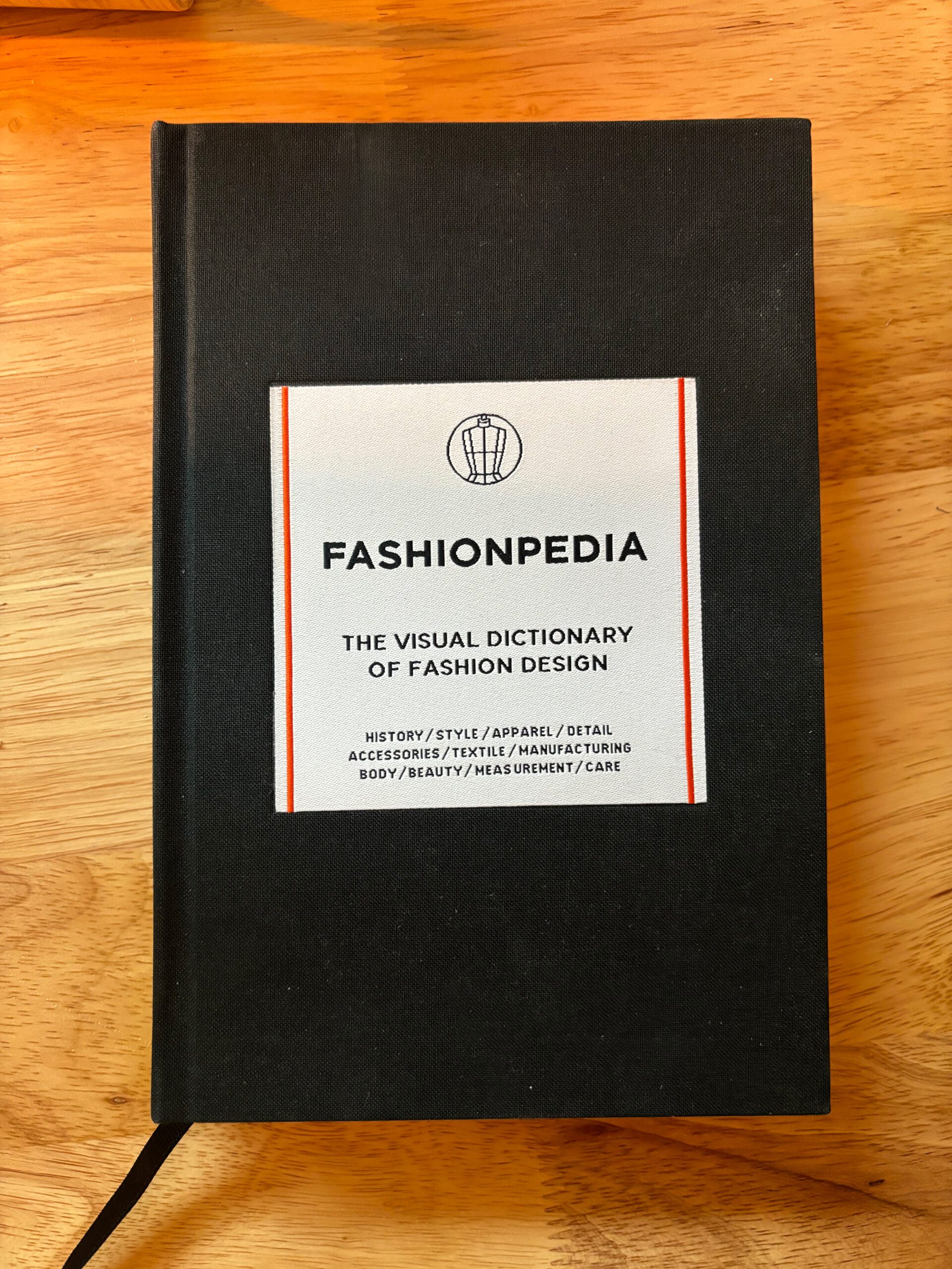 A book titled Fashionpedia containing many illustrations and information of various clothing styles and designs.